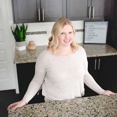 a woman standing in front of a granite counter top with her hands on her hips