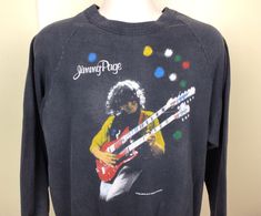 Vintage 1985 Jimmy Page The Firm raglan crewneck concert sweatshirt.  Fabric feels like soft cotton blend. Some overall fading, as shown in the photos.  No holes, no stains, no other issues. Approximate size L.  Please note measurements to avoid returns: laid flat measures 22.25" across chest (armpit to armpit), 24.75" length (top of center of collar on back to bottom of sweatshirt), 31" sleeve length (center of collar on back to end of sleeve). Rock Band Shirts, Classic Rock Bands, Raglan Sweatshirt, The Firm, Jimmy Page, Band Shirt, Sweatshirt Fabric, Band Shirts, Led Zeppelin