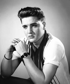 black and white photograph of a young man with his hands on his chin, posing for the camera