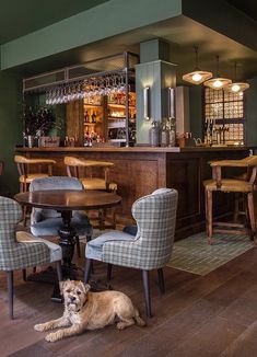 a dog laying on the floor in front of a table with chairs and a bar