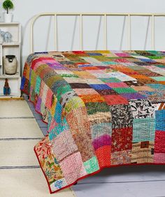 a bed with a multicolored quilt on it's headboard and foot board