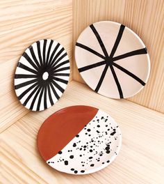 two plates with black and white designs on them sitting on a wooden surface next to each other