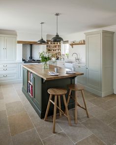 a kitchen with two stools next to an island in the middle of the room