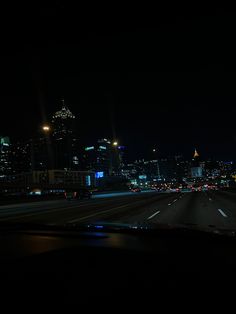 the city skyline is lit up at night with bright lights in the foreground and oncoming traffic