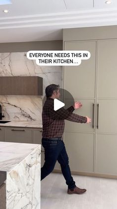 a man standing in a kitchen next to a refrigerator