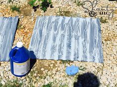 a blue bottle sitting on top of a gravel field next to a towel and other items