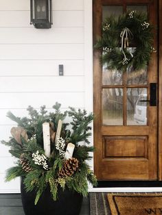 a planter filled with pine cones and greenery next to a door