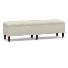 an upholstered bench with wooden legs and a buttoned seat on the back