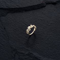 a gold ring sitting on top of a black stone surface with the word love written in it