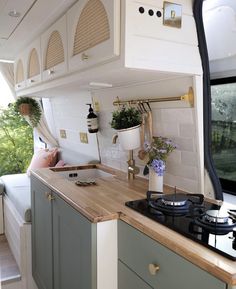 the interior of a camper with wood counter tops and green cabinets, along with an oven