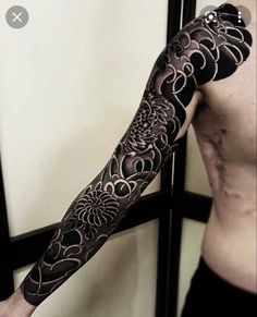 a man's arm covered in black and white tattoos with flowers on the side