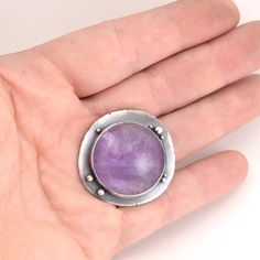 "This all sterling silver ring features a round amethyst, set on a recycled silver backplate, studded with small silver balls. The ring shank is about 8mm wide. The face of the ring is about 1.25\" x 1.25\" across. The ring has been oxidized and selectively brushed to highlight the details. The ring is US size 8.5. It can be enlarged on request in quarter sizes up to 9.5. Because of the width of the band, I'd suggest ordering a size 1/4 to 1/2 larger than normal. Please read my shipping and poli Sterling Silver Amethyst Ring With Large Stone, Unique Silver Amethyst Ring With Large Stone, Sterling Silver Amethyst Ring For Healing, Nickel-free Silver Amethyst Ring In Sterling Silver, Sterling Silver Cabochon Amethyst Ring, Silver Amethyst Cabochon Ring In Sterling Silver, Sterling Silver Amethyst Cabochon Ring, Sterling Silver Amethyst Ring With Cabochon, Silver Sterling Amethyst Ring With Round Stone