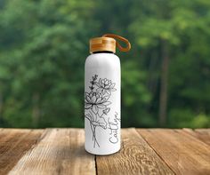 a white water bottle sitting on top of a wooden table with trees in the background