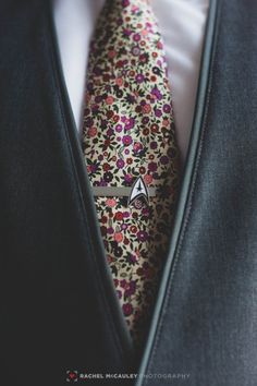 a man wearing a floral neck tie with a white shirt and black blazer jacket