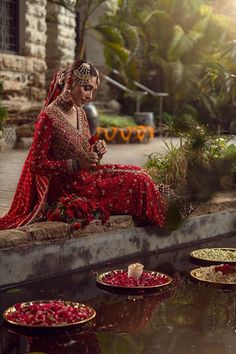 a woman in red dress sitting on ledge next to water