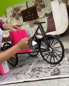 a woman sitting on the floor next to a bike with a pink box in it