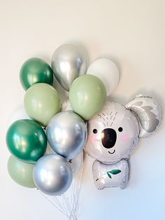 a bunch of balloons that are in the shape of a koala bear with green, white and silver balloons