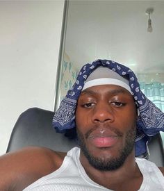 a man with a bandana on his head sitting in a chair looking at the camera