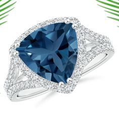 a blue diamond ring with white diamonds around it and palm leaves in the back ground