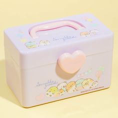 a pink and blue lunch box with a heart on it's lid sitting on a yellow surface