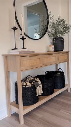 a wooden table topped with baskets under a mirror