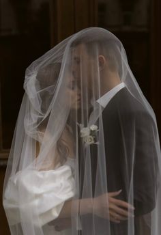 a bride and groom embracing under a veil