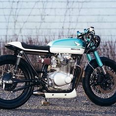 a blue and white motorcycle parked on top of a gravel road