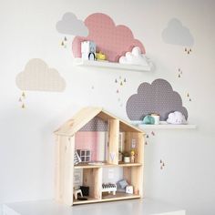 a doll house on top of a white table in front of clouds and raindrops