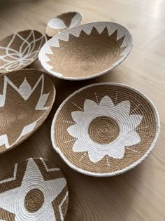 four brown and white woven baskets sitting on top of a wooden floor next to each other