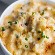 a white bowl filled with macaroni and cheese covered in green onion garnish