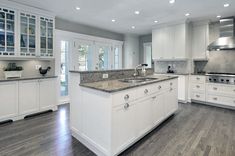 a kitchen with white cabinets and granite counter tops in an open floor plan for the home