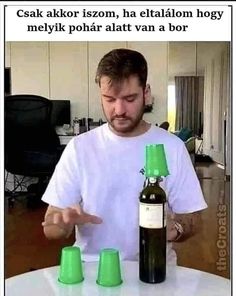 a man holding three green cups in front of a beer bottle on top of a table