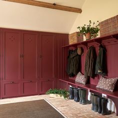 a room with red painted walls and lots of coats hanging on the coat rack,