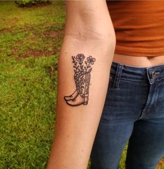 a woman with a tattoo on her arm is standing in the grass and holding flowers