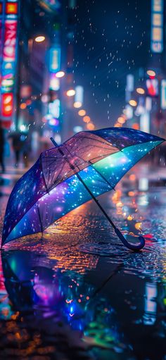 an open umbrella sitting on the side of a wet street in the rain at night