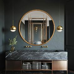 a bathroom with a marble counter top and gold accents on the mirror, along with two brass pendant lights