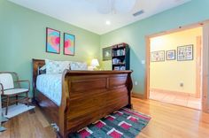 a bed room with a neatly made bed next to a chair and a book shelf