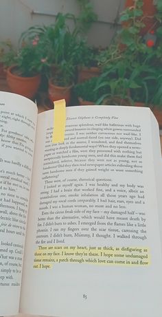 an open book with yellow stickers on it sitting in front of potted plants