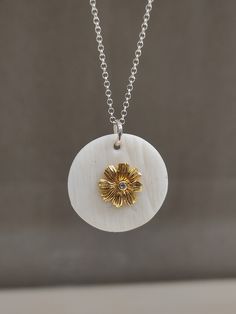 "This pendant necklace is made of white matte porcelain, the pendant is round and the surface is embossed, the center of the pendant is decorated with a silver gilded  flower which decorates it in the center a round zircon. The pendant is passed on a silver chain, with a handmade silver hook. It has a minimal design and is suitable for a casual elegant look. There may be a slight difference between the pieces, because they are all produced handmade one by one. The porcelain is left matte, in its natural texture , without any use of enamel and glazing, highlighting its beauty and its properties. Each piece is hand shaped by me before being fired in a kiln to 1240C. Important Note: The oxidization will gradually wear off eventually, depending on use, the chain will get a sort of a vintage lo White Medallion Necklace For Anniversary, Elegant White Round Disc Jewelry, White Flower Pendant Necklace For Anniversary, White Pendant Necklace With Flower Charm, White Medallion Necklace, White Round Pendant Jewelry With Flower Charm, White Engraved Round Pendant Jewelry, White Artisan Round Pendant Jewelry, White Sterling Silver Disc Jewelry