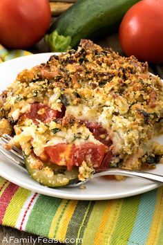 a white plate topped with a casserole covered in cheese and toppings next to tomatoes