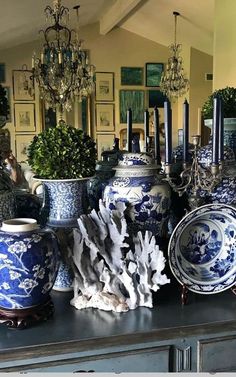 many blue and white vases on a table with candles in the middle one is surrounded by other decorative items