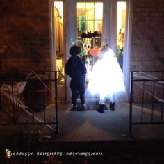 two children dressed up in costumes standing at the front door