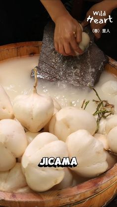 a person is cutting mushrooms into small pieces in a wooden bowl with liquid and herbs