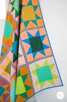 two colorful quilts hanging on the wall next to each other in an area with white walls