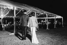 a man and woman walking under a tent at night