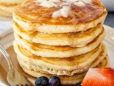 a stack of pancakes with syrup and fruit on a plate