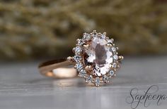 a ring with an oval shaped morganite surrounded by smaller round diamonds on a table