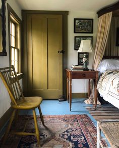 a bed room with a neatly made bed next to a wooden chair and a table