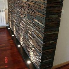 a wall made out of wood and stone with lights on the sides, along with a wooden floor