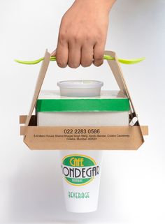 a person holding a box with food in it and a green spoon sticking out of it